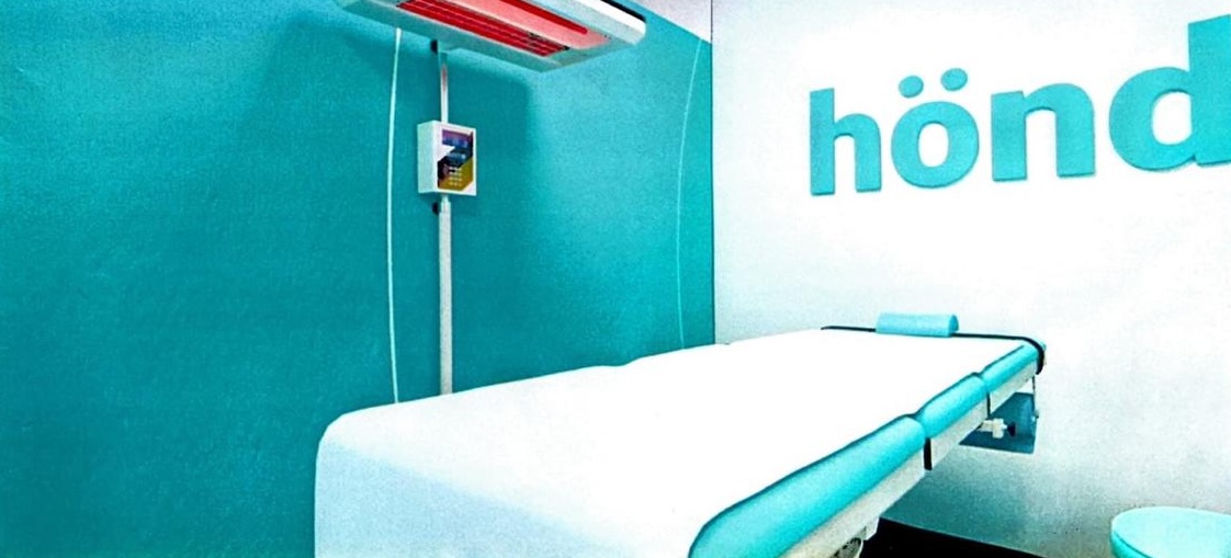 Sala de tratamiento hönd con camilla y equipamiento médico